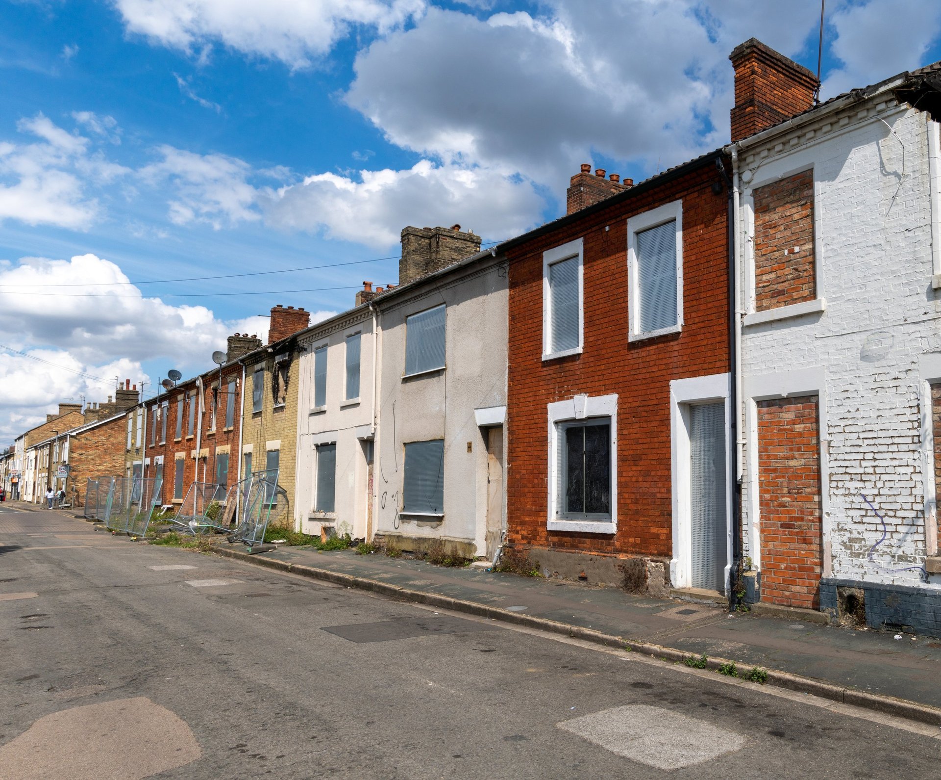 Row of colorful terraced houses on a residential street under blue sky with white clouds