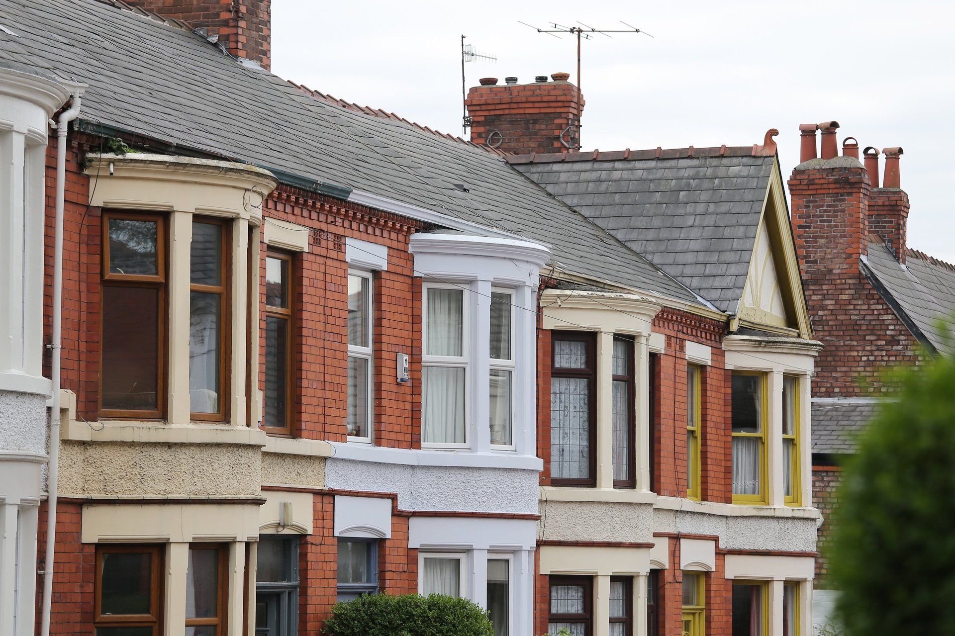 Row of Victorian terraced houses with red brick, bay windows, and varied colored doorways under slate roofs